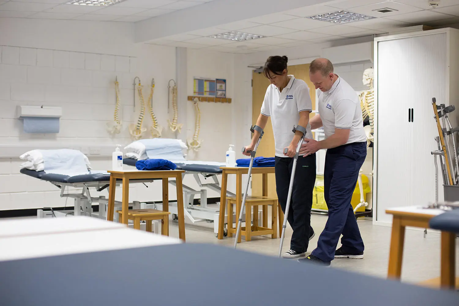 Physio student supporting a person on crutches