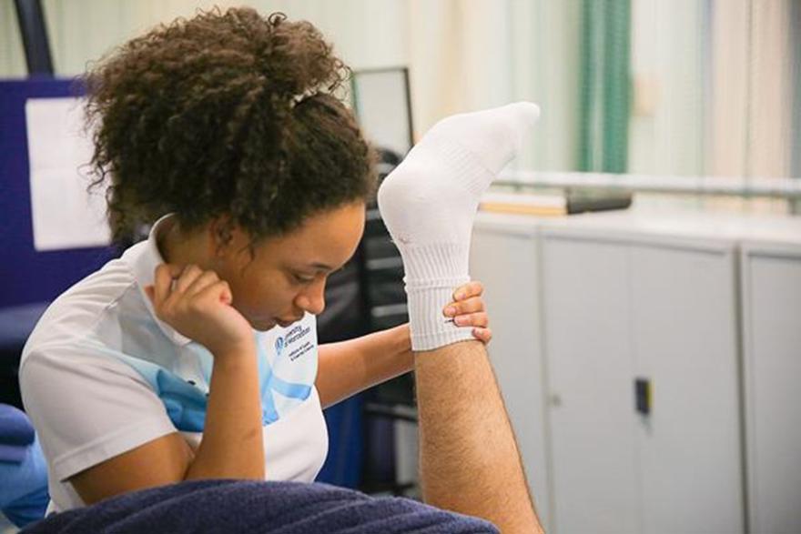 Woman stretching man's leg