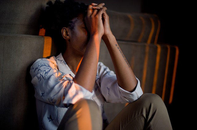 A person is crouched down on the floor looking extremely stressed