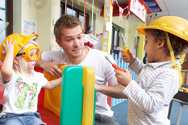 adult working with two children wearing yellow helmets
