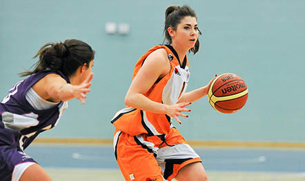 Basketballer dribbles the ball while a player from the opposite team tries to block