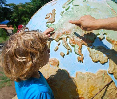 A child is pointing at Europe on a globe