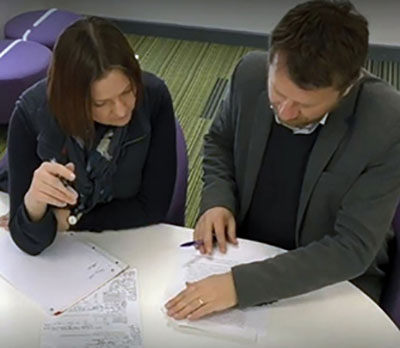 Two people are working together sitting at a table