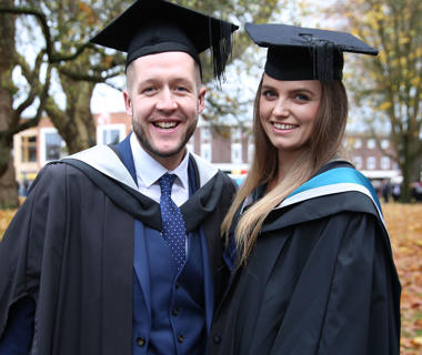 Male and female student in graduation robes