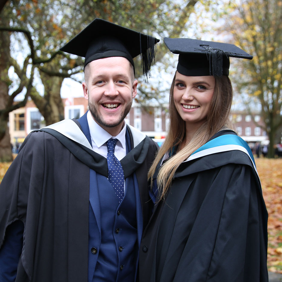 Male and female student in graduation robes