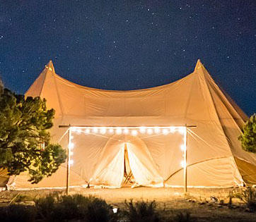 Beige tent at night with twinkling lights on the foreground