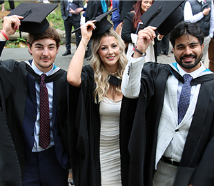 Three graduates lifting their caps