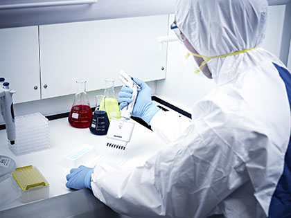 Man in lab coat blue gloves at a white desk
