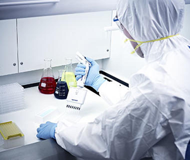 Man in lab coat blue gloves at a white desk