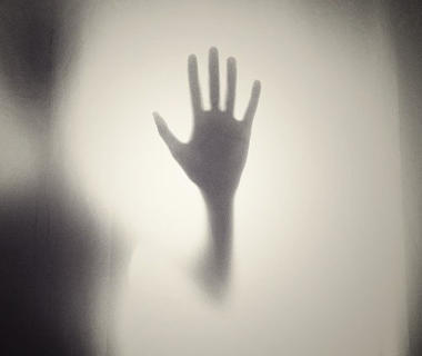 A ghostly hand is pressed against a window