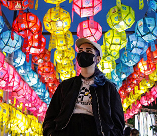 A student wearing a face mask with strings of colourful lanterns in the background