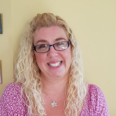 Portrait of a smiling woman with blonde hair and glasses