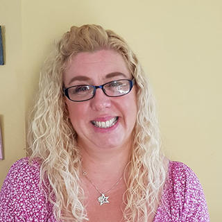 Portrait of a smiling woman with blonde hair and glasses