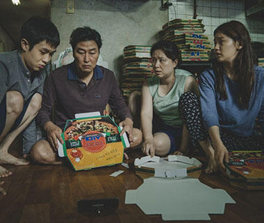 A shot from the film parasite of a family sitting around pizza boxes