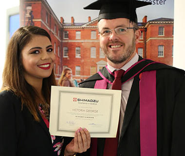 student and lecturer on graduation robes holding a certificate
