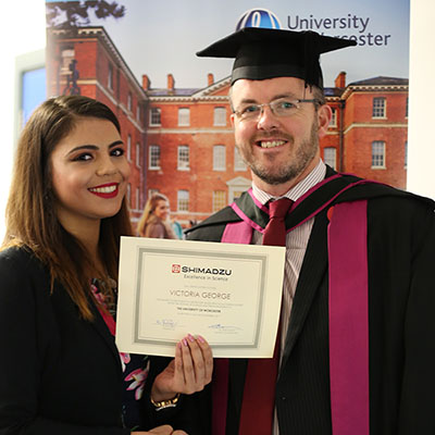 student and lecturer on graduation robes holding a certificate