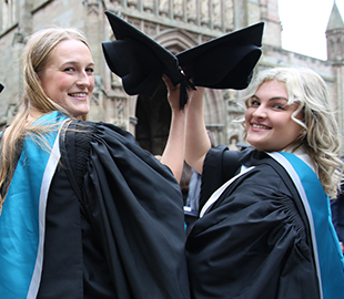two graduates lifting their caps