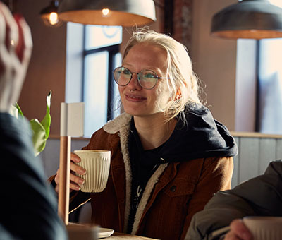 A smiling student is drinking a cup of coffee