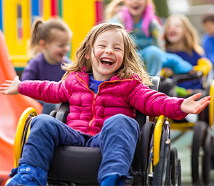 Girl laughing whilst playing in her wheelchair