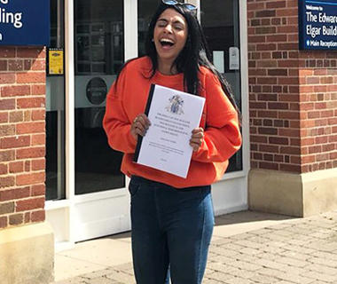 Laughing girl in an orange top holding a white file