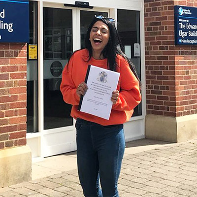 Laughing girl in an orange top holding a white file