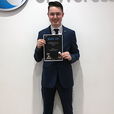 Young man in a blue suit holding a black poster