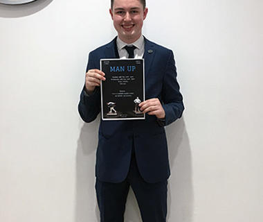 Young man in a blue suit holding a black poster