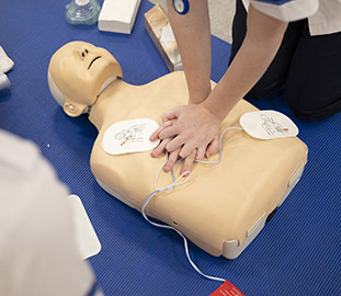 A pair of hands applying cpr to a dummy