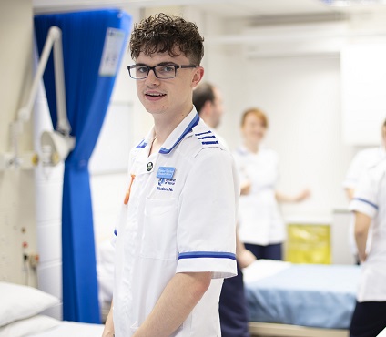 Male nurse in a white uniform wearing glasses