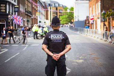 A police office standing with their back to the camera in the middle of the road