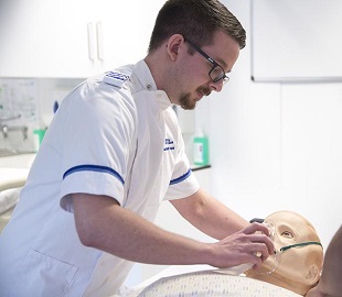 male nurse leaning over a prosthetic figure