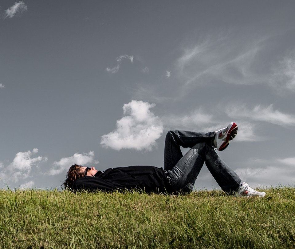 a man is lying on some grass staring up at the sky