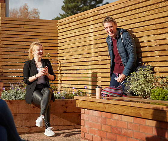 A group of students are laughing and standing together having coffee