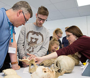 Students and lecturers at a table of bones and skulls