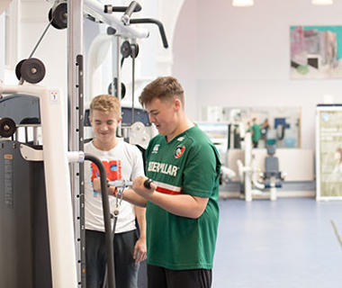 two young men beside gym equipment