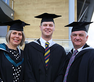 two mature students and a young man in graduation robes
