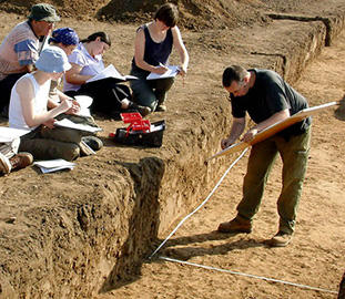 students writing notes beside a trench