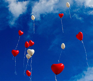 red and white heart-shaped balloons in a blue sky